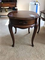 Front view of the wooden end table showing drawer and curved legs.