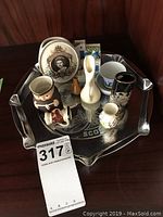 Silver plated tray holding assorted small souvenir figurines and mini vases including commemorative plate and thematic items.