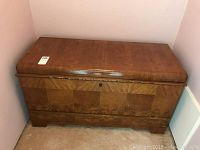 Front view of the wooden cedar chest with a smooth varnished wood finish and keyhole on the front.