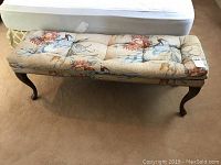 Front view of upholstered bench showing floral and bird patterned fabric and Queen Anne style legs.