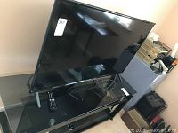 LG 50-inch TV on glass stand from front, showing stand and remote