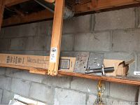 Two adjustable jack posts stored on a wooden shelf with cardboard boxes, showing metal parts and packaging labels.