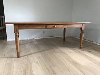 Full view of rectangular pine table showing turned legs and central drawer.