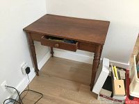 Front and side view of the solid wood table showing the dovetailed drawer partially opened and turned legs