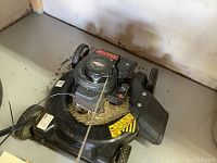 Top front view of black Yard Machines push lawn mower with Briggs & Stratton engine and grass clippings on the mower deck.