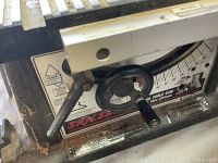 Close-up of Skilsaw adjustable angle gauge and control dial showing metal parts with rust and usage marks.