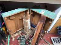 View of antique wooden toolbox opened with various vintage carpenter tools spread inside and outside, showing wooden levels, hand planes, and auger bits
