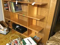 Left side view of wooden shelf with various compartments and some items on it.