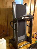 Side view of folded treadmill showing overall condition and foldable track design.