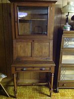 Front view of the two-piece secretary desk showing upper glass cabinet and lower fold-down work surface