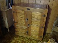Front view of closed ice box showing four-panel wooden doors and metal latch