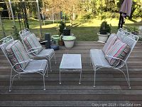 Full view of patio set on deck showing two chairs, one bench with cushions, and a table.