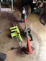 Photo of Gardena weed eater, Black & Decker hedge trimmer, and Poulan chain saw on garage floor showing full lot.