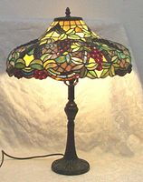 Full view of the stained glass table lamp showing the grapevine detailed shade and metal base.