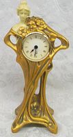 Front view of Art Nouveau style clock showing the female figure, clock dial with Roman numerals, and floral decoration.