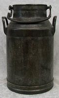 Front closed view of dark metal antique milk can with attached handle and side handles