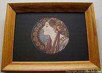 Frontal view of the framed Mucha print highlighting the circular image of a woman in profile and the wooden frame.