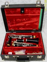 Clarinet pieces and accessories inside open hard case lined with red velvet