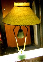 Assembled lamp with green parchment shade, gold-tone metal support, green base; all lights off