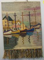 Full view of the rectangular woven jute wall hanging with five sailboats, houses in background, and tassel fringe bottom.
