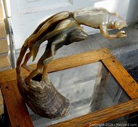Front angle showing three carved frogs emerging from curved horn base