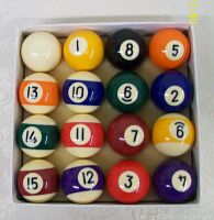 Close-up of 16 mini billiard balls arranged in four rows inside white box.