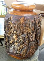 Front angle view of the carved wood vase showing the natural bark texture and polished turned wood top.