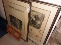 Two large framed Lebadang drawings leaning against wall with visible artist seals and signatures.