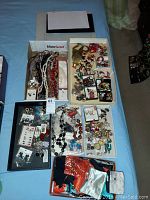 Overview photo of multiple boxes containing a variety of costume jewelry such as necklaces, pins, earrings, and bags on a blue surface