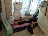 Overview of lot showing dress form with white bra, sewing machine case, rolls of fabric, and various sewing materials.