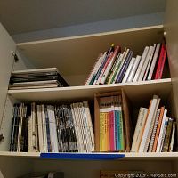 Two shelves of books and magazines showing various titles and bindings including spiral and hardcover, mostly art and reference related.