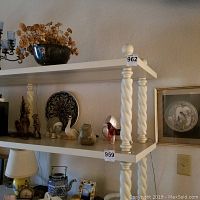 Shelf with multiple items including decorative plate, glass and ceramic figurines, dried flower arrangement.