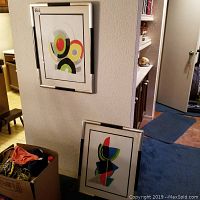 Two framed abstract prints by Sonia Delaway—one hung on wall, one leaning—showing silver frames with black accents