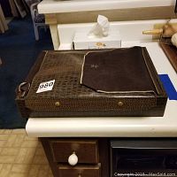 Closed brown crocodile-patterned leather cutlery case with felt lining
