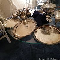 Overall lot on glass table including three serving trays, tea service pieces, chafing dish, serving box, storage bags