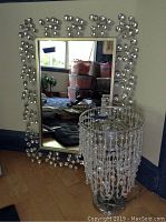 Full view of the mirror on floor showing its rhinestone bubble border and the lamp with bead fringe shade in front.
