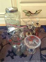 Wide shot of all glassware and metal items inside a room on a carpeted floor, showing a large Yorkshire Glassware dispenser, martini glasses, the metal server and sugar dish, the glass bowl, and vase.