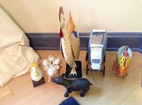 Photo showing the full group of vintage metal animal banks and figurines including standing chicken, rolling cow and chickens, duck and pig banks.