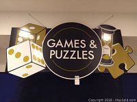 Front view of large wooden Games & Puzzles sign with dice, hourglass, and puzzle piece