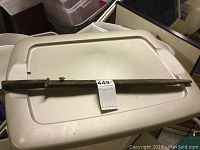 Bayonet sheathed and laid flat on a white plastic surface to show full length and sheath condition.