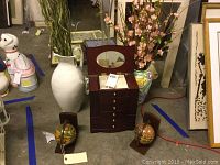Overall view showing jewelry cabinet, two tall ceramic vases with artificial flowers, and globe bookends on floor.