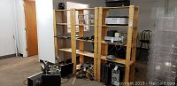 View of three wooden shelving units with shelves containing audio and electronic equipment