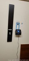 Wall mounted Lathem Time 800P time clock with plugged in power cord and black vertical card holder beside it.
