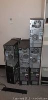 Stack of nine black and gray computer towers showing rear panels with fans and ports