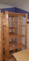 Full view of wooden shelving unit showing front and side with five shelves.