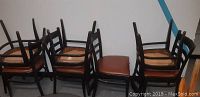 Photo showing all seven chairs grouped together, ladderback style with brown vinyl seats.