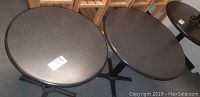 Top view of two black round tables placed side by side, size difference noticeable.