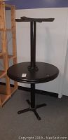 Round table upside down showing black metal pedestal base and mounting hardware.