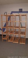 Front view of four tall wood shelving units with five shelves each, arranged side by side.