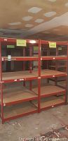Front view of two red steel frame shelving units with particle board shelves